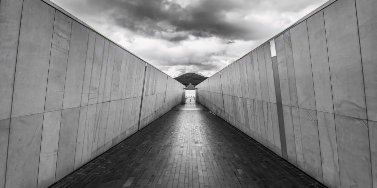 Symmetrical walkway in Canberra with dramatic clouds and modern architecture.