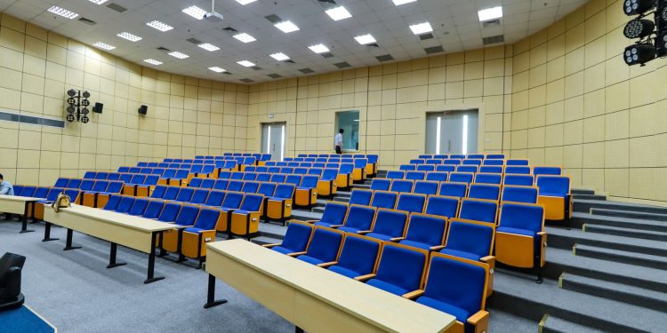 Spacious lecture hall with blue seats and desks ready for students.