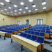 Spacious lecture hall with blue seats and desks ready for students.