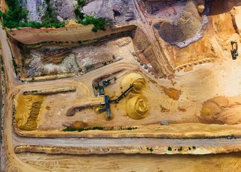 Aerial shot of a quarry with machinery extracting and processing materials.