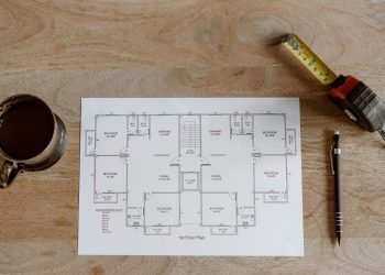 Top view of set of plan of room with tape measure and pen for work for architect with cup with coffee on wooden table in soft daylight