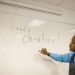Teacher writes 'No Cheating!' on whiteboard during classroom instruction.
