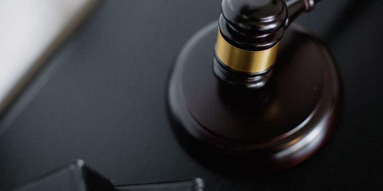 From above of wooden gavel on round surface near folders on table in courtroom