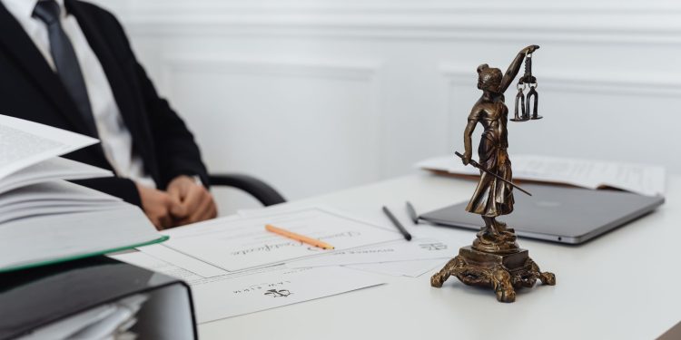 A legal professional's workspace featuring Lady Justice statue, documents, and a laptop.