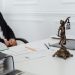 A legal professional's workspace featuring Lady Justice statue, documents, and a laptop.