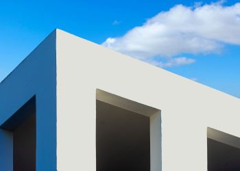 Modern minimalist architecture with white facade and clear blue sky background.