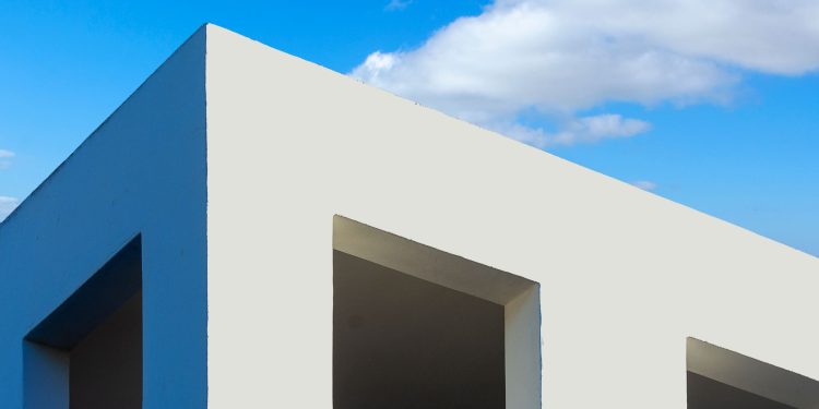 Modern minimalist architecture with white facade and clear blue sky background.