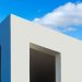Modern minimalist architecture with white facade and clear blue sky background.