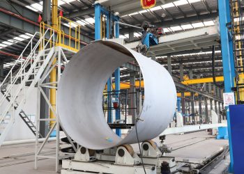 A spacious industrial factory scene showcasing steel pipe production with modern machinery.