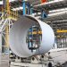 A spacious industrial factory scene showcasing steel pipe production with modern machinery.