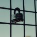 Close-up of a steel padlock on a mesh fence, symbolizing protection and security.