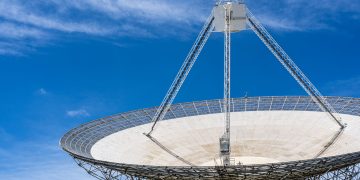 A large satellite dish with a clear blue sky in the background, showcasing modern communication technology.