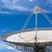 A large satellite dish with a clear blue sky in the background, showcasing modern communication technology.