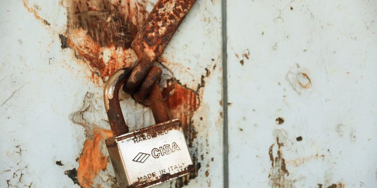 Close-up of a rusty padlock on a weathered wall, showcasing vintage charm.