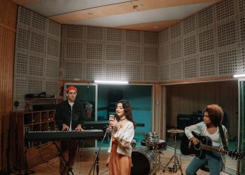 A diverse band practicing music in a professional recording studio setting.