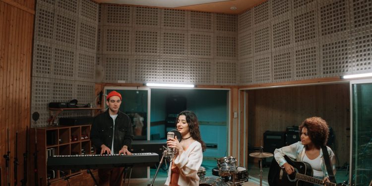 A diverse band practicing music in a professional recording studio setting.