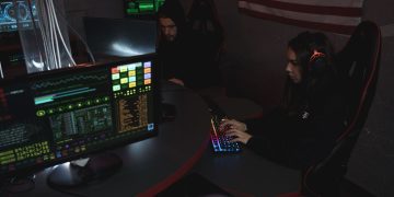 Cybersecurity professionals working on computer systems, focusing on data protection in a dimly lit room.