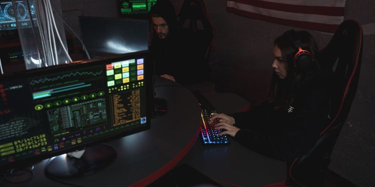 Cybersecurity professionals working on computer systems, focusing on data protection in a dimly lit room.