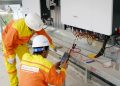 Two electrical engineers installing and testing solar power systems wearing safety gear at a construction site.