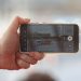 A hand holding a smartphone recording a video of a car scene outdoors. Captured in Balatonfőkajár, Hungary.