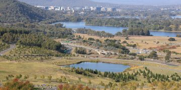 Scenic aerial shot of Canberra, showcasing lush greenery, lakes, and city skyline.