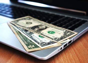 Close-up of US dollar bills placed on a laptop symbolizing digital finance and economy.