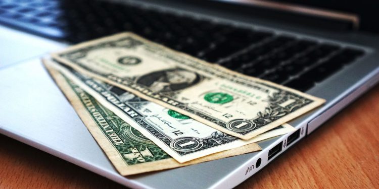 Close-up of US dollar bills placed on a laptop symbolizing digital finance and economy.