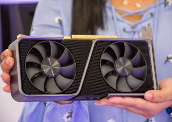 Detailed shot of hands holding a modern graphics card indoors.