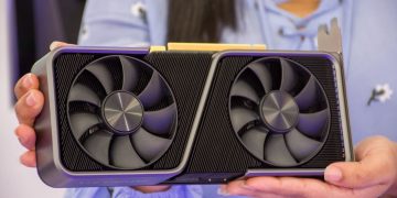 Detailed shot of hands holding a modern graphics card indoors.