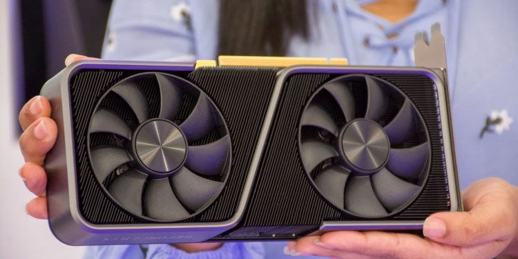 Detailed shot of hands holding a modern graphics card indoors.