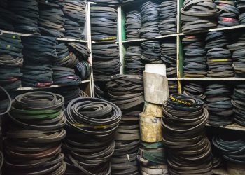A cluttered storage room filled with stacks of rubber belts and industrial equipment.