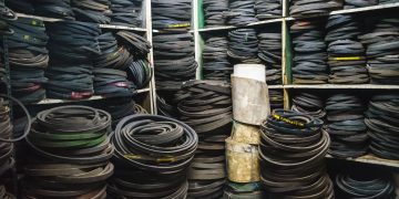 A cluttered storage room filled with stacks of rubber belts and industrial equipment.
