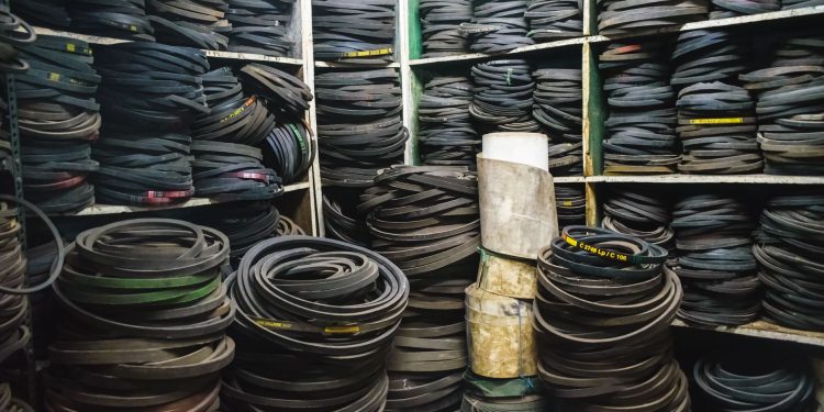 A cluttered storage room filled with stacks of rubber belts and industrial equipment.