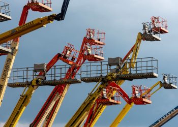 Vibrant boom lifts reaching skyward, showcasing industrial machinery against a clear blue backdrop.