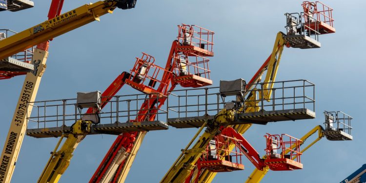 Vibrant boom lifts reaching skyward, showcasing industrial machinery against a clear blue backdrop.
