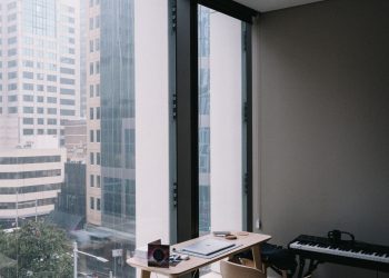 Elegant home office setup overlooking Sydney's urban architecture through large windows.