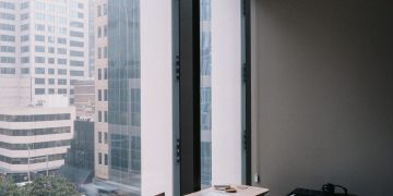 Elegant home office setup overlooking Sydney's urban architecture through large windows.