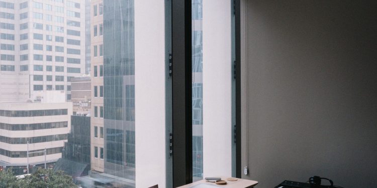 Elegant home office setup overlooking Sydney's urban architecture through large windows.