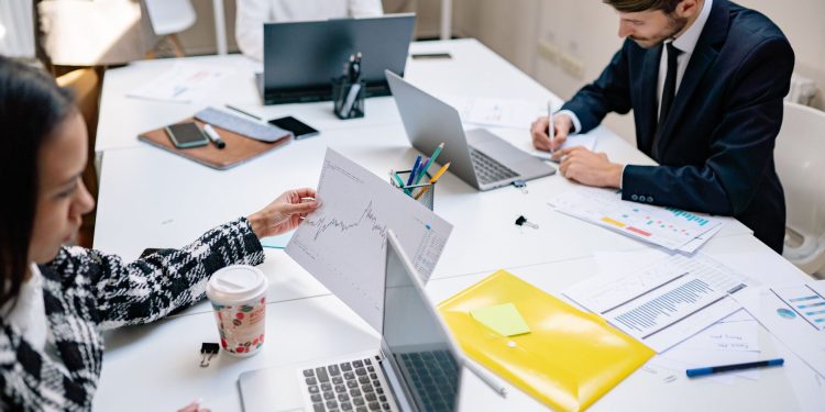 Professionals collaborating in a modern office with laptops and documents, focusing on teamwork.