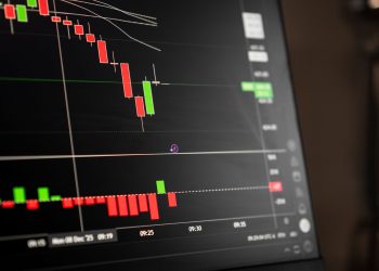 A close-up of a digital screen showing stock market candlestick chart data.