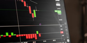 A close-up of a digital screen showing stock market candlestick chart data.