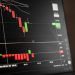 A close-up of a digital screen showing stock market candlestick chart data.
