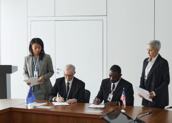 Business leaders signing a significant agreement in a conference room setting.