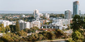 A beautiful day view of Perth city skyline with lush greenery and Swan River.