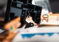 Keys with a house model, Euro bills, and charts suggesting real estate and financial themes.