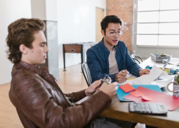 Two young entrepreneurs brainstorm ideas in a modern office setting, fostering innovation and collaboration.