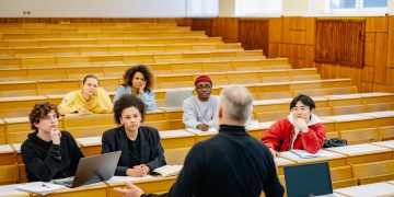 Professor teaching a diverse group of students in a university lecture hall.