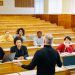 Professor teaching a diverse group of students in a university lecture hall.
