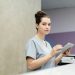 Professional receptionist using a tablet device at a modern office reception desk.