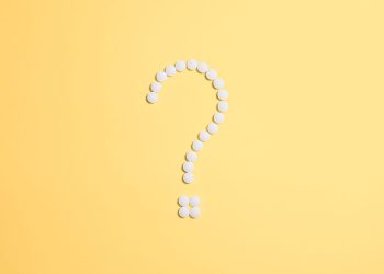 White pills arranged into a question mark shape on a vibrant yellow background.